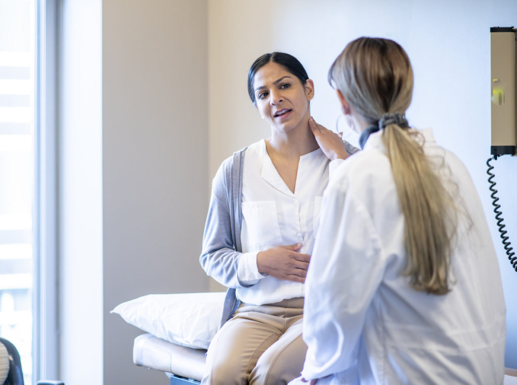 Woman explaining her neck pain to doctor