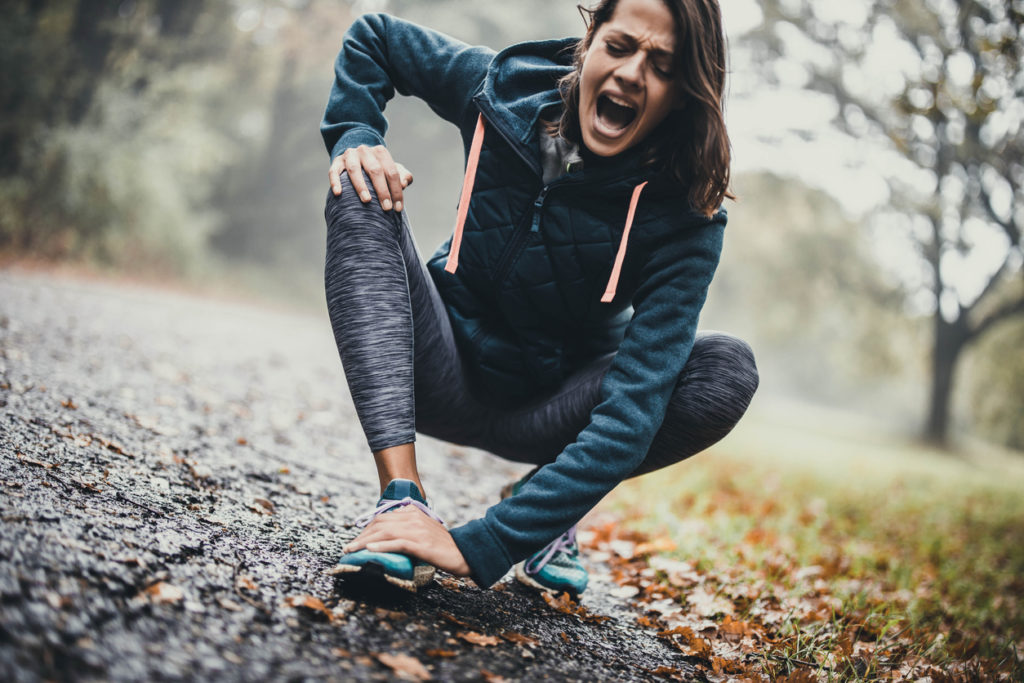 Athletic woman screaming after injuring her foot at the park