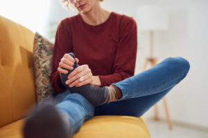 Woman sitting on the couch with foot pain