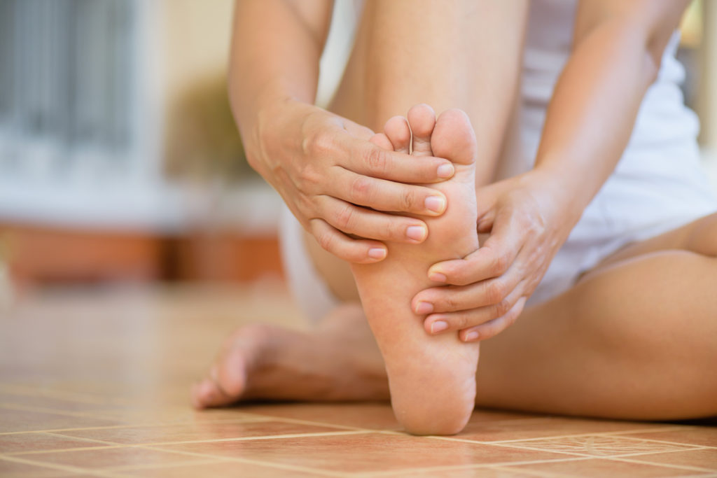 Woman sitting on the floor with foot pain