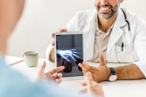 Cropped shot of an unrecognisable doctor sitting with his patient and showing his x-rays on a digital tablet