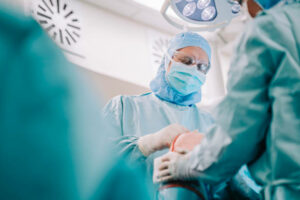Team of surgeons operating a patient knee in the hospital operating room. Surgical team in medical scrubs in the midst of knee replacement operation.