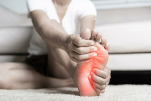 woman feeling pain in her foot at home