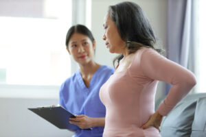 The doctor is diagnosing the patient's back pain