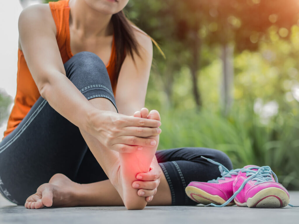 Soft focus woman massaging her painful foot while exercising