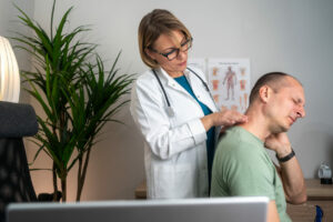 A female neck and spine specialist conducts a medical exam for neck pain on her patient.