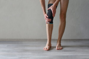 A person is wearing a knee support brace on his leg due to knee pain from a meniscus tear.