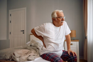 Elderly man feeling pain in his lower back in the morning.